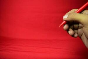 Man hand with red pen writing on red background photo