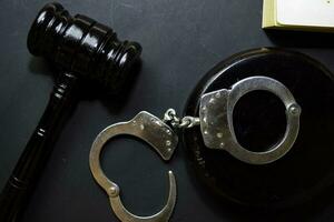 handcuffs and black gavel isolated on black background. Justice and law concept photo