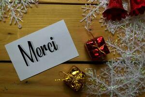 Merci write on white paper with wooden backgroud. It means Tank You. Frame of Christmas Decoration. photo