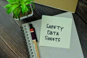 Safety Data Sheets write on sticky notes isolated on Wooden Table. photo