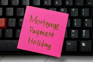 Mortgage Payment Holiday write on sticky note isolated on wooden table. photo