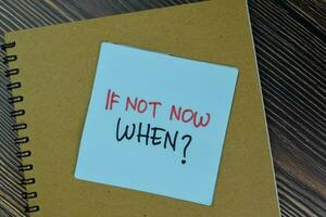 If Not Now When write on sticky notes isolated on Wooden Table. photo