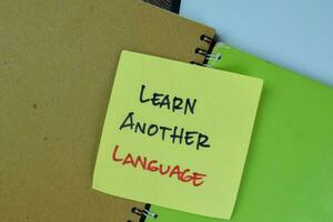 Concept of Learn Another Language write on sticky notes isolated on Wooden Table. photo