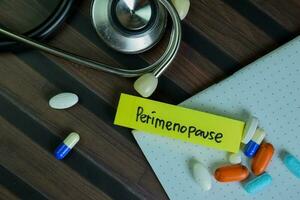 Perimenopause write on sticky notes isolated on Wooden Table. photo
