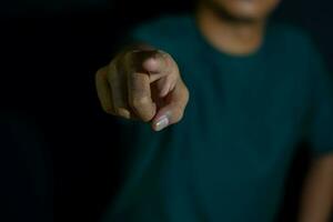 joven hombre demostración dedo eso medio hacer tu elección en oscuro negro antecedentes. selectivo atención en dedo foto