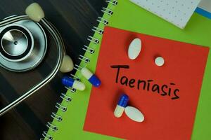 Taeniasis write on sticky notes isolated on Wooden Table. Medical or Healthcare concept photo