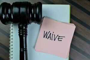 Concept of Waive write on sticky notes with gavel isolated on Wooden Table. photo