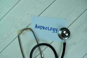 Concept of Andrology write on sticky notes with stethoscope isolated on Wooden Table. photo