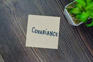 Covariance write on sticky notes isolated on Wooden Table. photo