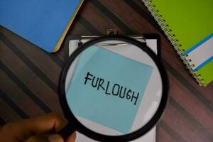 Furlough write on sticky notes with magnifying glass isolated on office desk photo