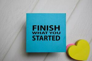 Finish What You Started write on a sticky note isolated on Office Desk. photo