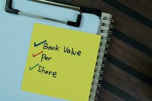 Concept of Book Value Per Share write on a sticky notes isolated on Wooden Table. photo