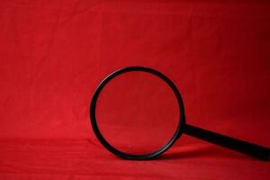 Magnifying glass on red background photo