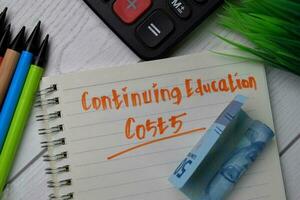 Continuing Education Costs text write on a book isolated wooden table. photo