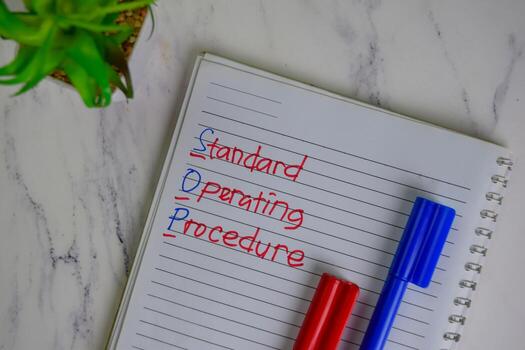 SOP - Standard Operating Procedure write on a book isolated on Wooden Table. photo