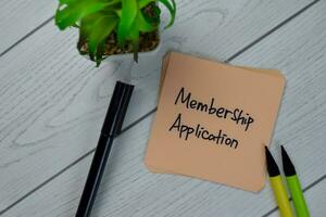 Membership Application write on sticky notes isolated on Wooden Table. photo