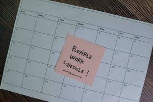 Flexible Work Schedule write on sticky notes isolated on Wooden Table. photo