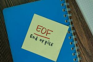 EOF - End Of It write on sticky notes isolated on Wooden Table. photo