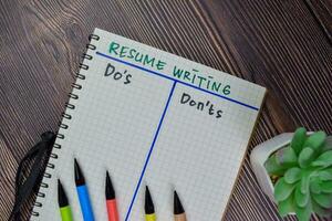 Resume Writing and Do's or Don'ts write on a book isolated on Wooden Table. photo