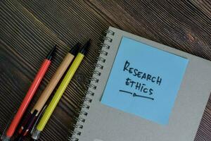 Research Ethics write on sticky notes isolated on Wooden Table. photo