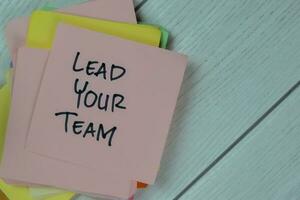 Concept of Lead Your Team write on sticky notes isolated on Wooden Table. photo