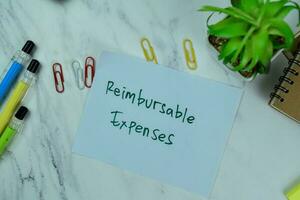 Concept of Reimbursable Expenses write on sticky notes isolated on Wooden Table. photo