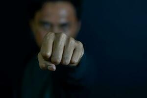 Young man showing finger it means serious or boxing, fighting concept on dark black background. selective focus on finger photo