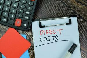 Direct Costs write on a paperwork isolated on Wooden Table. photo