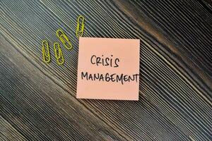 Concept of Crisis Management write on sticky notes isolated on Wooden Table. photo