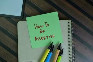 How to be Assertive write on sticky notes isolated on Wooden Table. photo
