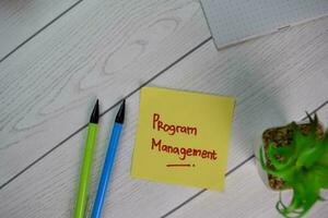 Program Management write on sticky notes isolated on Wooden Table. photo