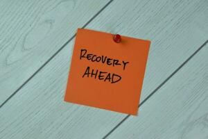 Concept of Recovery Ahead write on a book isolated on Wooden Table. photo