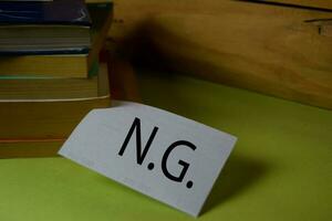 NG write on a sticky note isolated on Office Desk. Business Document concept photo