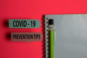 Covid - 19 Prevention Tips write on a sticky note isolated on Office Desk. Healthcare Medical concept photo