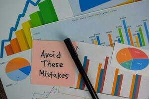 Avoid These Mistakes write on sticky notes isolated on Wooden Table. Stock market concept photo