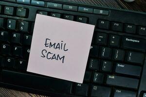 Email Scam write on sticky notes isolated on Wooden Table. photo