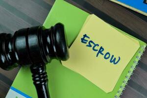 Concept of Escrow write on sticky notes with gavel isolated on Wooden Table. photo