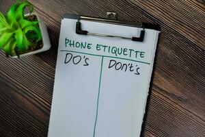 Concept of Phone Etiquette Do's and Don't's write on paperwork isolated on Wooden Table. photo