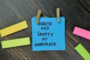 Health and Safety At Workplace write on sticky notes isolated on Wooden Table. photo