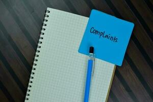 Complaints write on sticky notes isolated on Wooden Table. photo