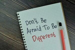 Concept of Don't Be Afraid To Be Different write on a book isolated on Wooden Table. photo