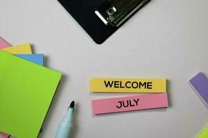 Welcome July text on sticky notes with office desk concept photo