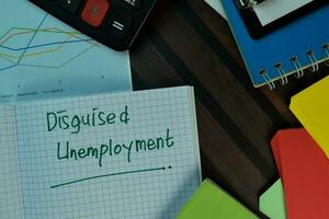 Disguised Unemployement write on a book isolated on Wooden Table. Business or Finance concept photo