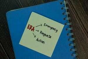 ERA - Emergency Response Action write on sticky notes isolated on Wooden Table. photo