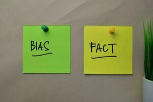 Bias and Fact write on sticky notes isolated on office desk. photo