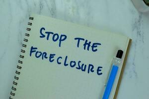 Concept of Stop The Foreclosure write on a book isolated on Wooden Table. photo