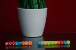 Possible impossible text at colorful wooden block on red background. Desk office and education concept photo