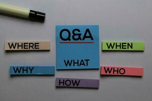 Q and A. Where, Why, What, When, Who, How write on sticky notes. Isolated on white table background photo