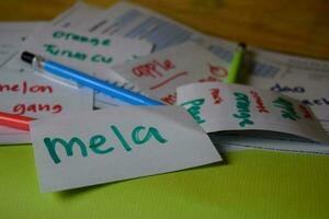 Mela write on a sticky note its mean apple isolated on Office Desk. Learning Italian Language concept photo