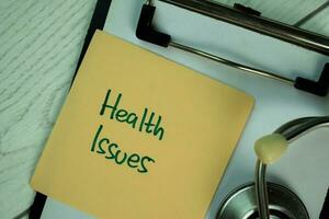 Health Issues write on sticky notes isolated on Wooden Table. photo